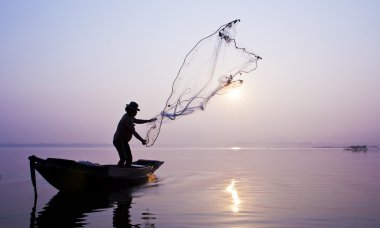 Fishermen are catching fish with a cast net. clipart