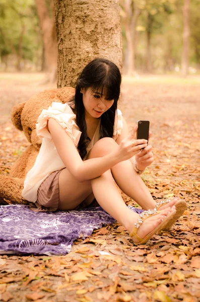 Asijská dívka hraje mobilní telefon — Stock fotografie