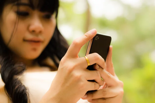 Asiatisk tjej spelar mobiltelefon Royaltyfria Stockfoton