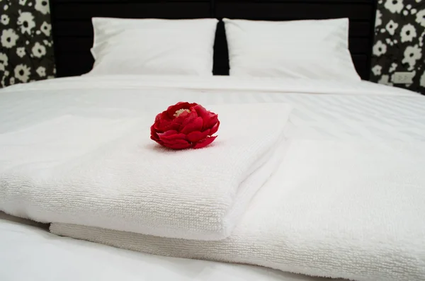 Röd ros på vit handduk i hotellrum Stockbild