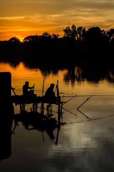 Dois silhueta pescador contra o pôr do sol Imagem De Stock