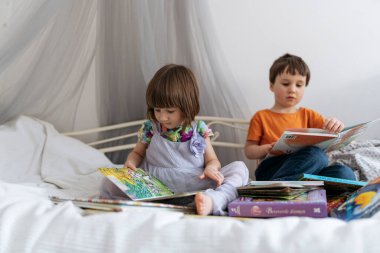 İki kardeş kanepede kitap okuyor. 