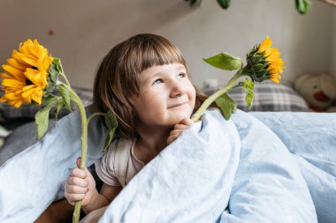 Elinde ayçiçeği tutan küçük bir kızın portresi.