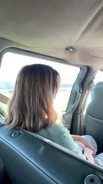 Back view of a young blond woman sitting in a car. High quality FullHD footage