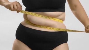 Aşırı kilolu beyaz kadın beline bant sarar. Yine de yüksek kaliteli video..