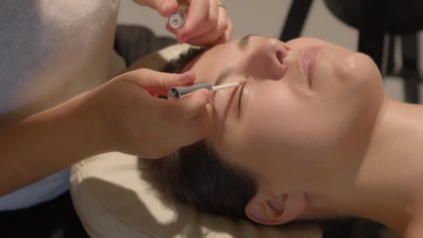 Cosmetoloog brengt lijm en siliconen pad voor wimpers lamineren procedure. Zijaanzicht videobeelden van hoge kwaliteit. — Stockvideo