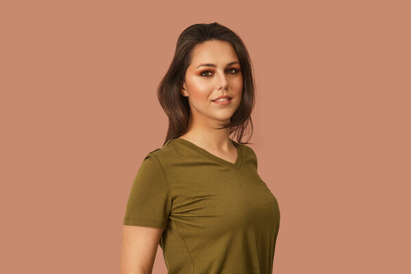 Young caucasian woman with make-up standing half turn and looking in the camera. Khaki t-shirt on seamless background medium shot. Stock Picture
