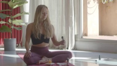 Güzel sarışın beyaz kadın adaçayı lekeli çubuklarla meditasyon yapıyor. Video görüntüleri hala çekiliyor..