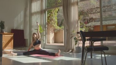 Siyah spor sutyenli güzel esnek beyaz kız ve yoga yapan taytlar ve evde duran kafa. 4k video kaydı