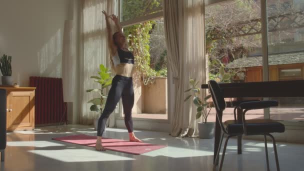 Jovem bela loira caucasiana yogui mulher em um sutiã esportivo e leggins praticar pose roda em um lugar espaçoso. Imagens de vídeo 4k — Vídeo de Stock