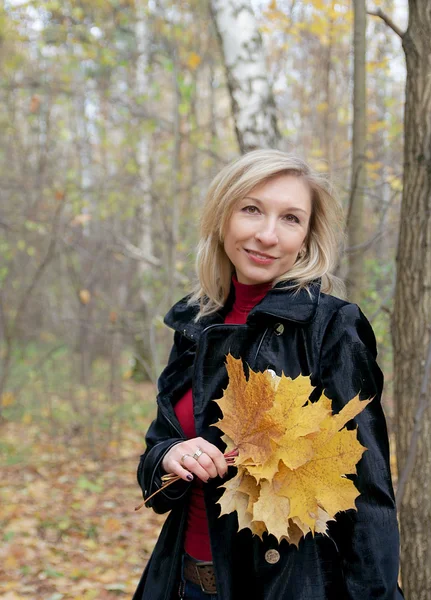 Frau hält Herbstlaub in der Hand — Stockfoto