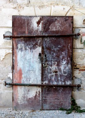 Kapı tokmağı ve tamamen kapalı olan eski bir demir kapının anımsatıcı görüntüsü.