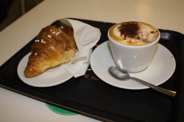 Kapüşonlu ve kruvasanlı bir kahvaltı görüntüsü. 