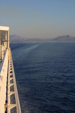 evocative image of the side of a ferrywhile sailing with the coast in the background