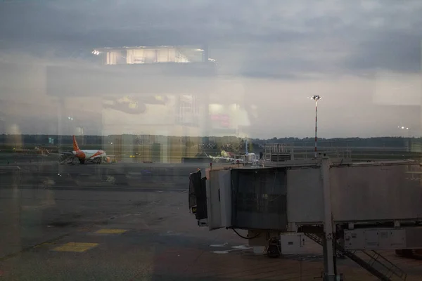 悪い日に窓から見える空港の搭乗用スリーブ又は伸縮式ガングウェイ 搭乗口 の最後の部分の感動的なイメージ — ストック写真