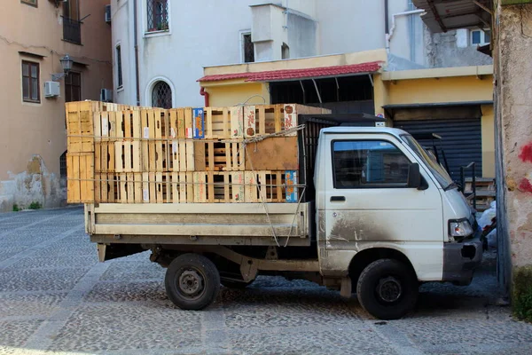 空の果物や野菜の箱でイタリアの街の通りに停められた小さなバンの印象的なイメージ — ストック写真
