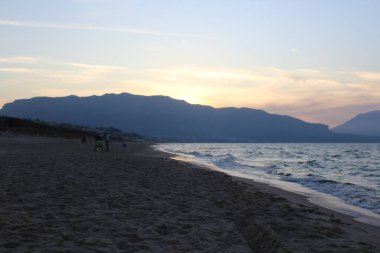 Denizin üzerinde gün batımının anımsatıcı görüntüsü. Arka planda burunların silueti var.