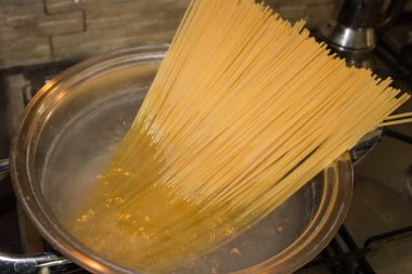 Spagettiyi kaynayan suyla dolu bir tencereye koy ve pişirilmeyi bekle.