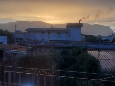 Denizin üzerinde gün batımının anımsatıcı görüntüsü. Arka planda burunların silueti var.