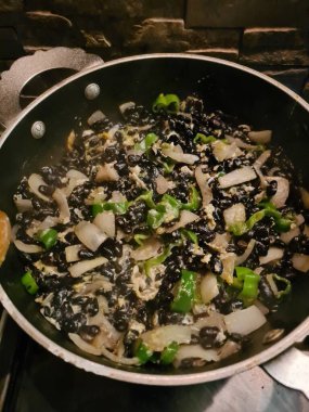 Siyah fasulye, soğan ve bibere dayalı vejetaryen bir tencerede yemek pişirmenin canlandırıcı görüntüsü.