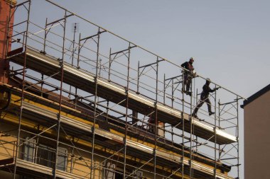 evocative image of workers engaged in assembling a scaffolding for a buildingto be restructured