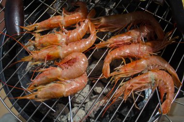 evocative close-up image of king prawns on the BBQ grill ready to be cooked