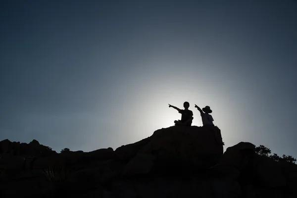 Duas crianças apontando, sentadas na rocha — Fotografia de Stock