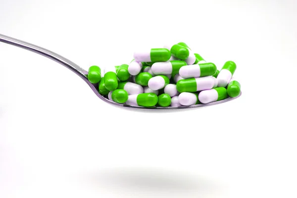Spoon with green capsules — Stock Photo, Image