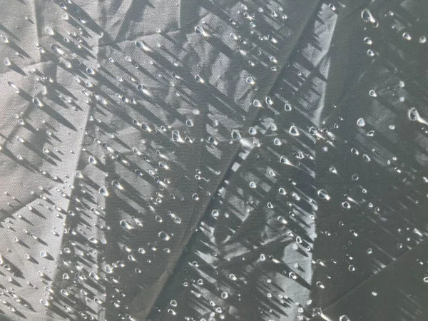 Sabahın erken saatlerinde güneş ışığının beyaz polyester kumaş çadırın her tarafına düştüğü aşırı yakın çekim çiğ damlaları.