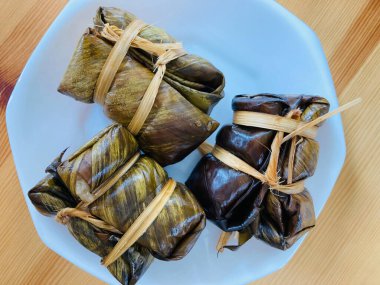 Kao Tom Çamuru adlı geleneksel Tayland tatlılarından üç çift beyaz bir tabakta doğal açık kahverengi kauçuk tahta masaya oturdular.