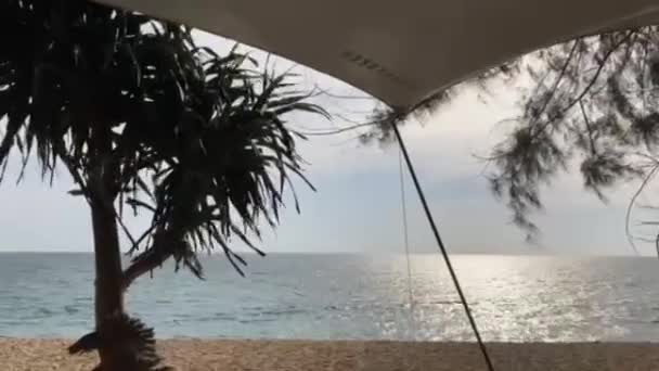 光天化日之下 从左向右俯瞰着在海滩上闪闪发光的海面和海滨的松木和松木景观的卷曲帐篷帆布的镜头 — 图库视频影像