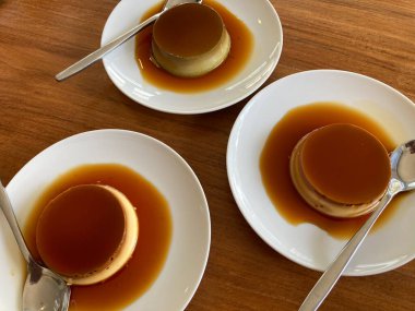 tatlı vanilya ve yeşil çay karamel kremalı tatlı beyaz tabaklar üzerinde gümüş kaşıklar kahverengi ahşap masa