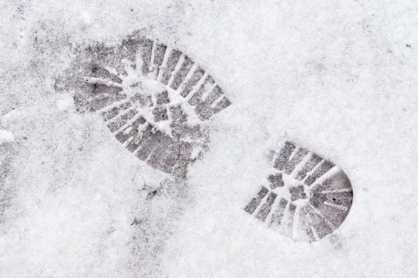 Om snöavtryck av sulan på skon med ett stort mönster för säker förflyttning på snötäckta och isiga trottoarer Royaltyfria Stockfoton