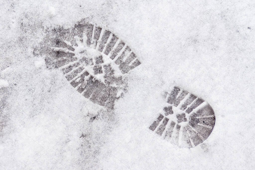 on the snow imprint of the sole of the shoe with a large pattern for safe movement on snow-covered and icy sidewalks