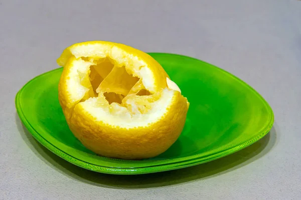 Limão, cortado e mal espremido, está em uma placa verde — Fotografia de Stock