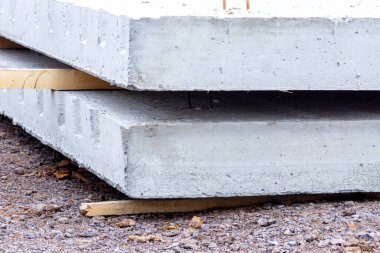 güçlendirilmiş beton levhalar, bir inşaat projesi uyarınca kurulum bekleyen ahşap uzay araçları üzerinde yatar.