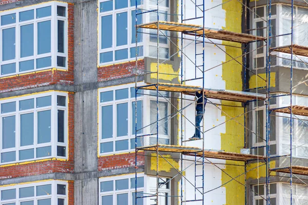 Trabajar en altura para aislar las paredes de un edificio residencial utilizando andamios — Foto de Stock