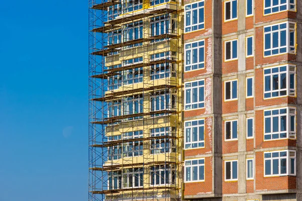 a multi-storey residential building under construction has scaffolding for external wall insulation with mineral wool, selective focus