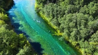 Bir grup turist akıntıya kapılıp güneşli havanın ve ormanın güzelliğinin tadını çıkarıyor.