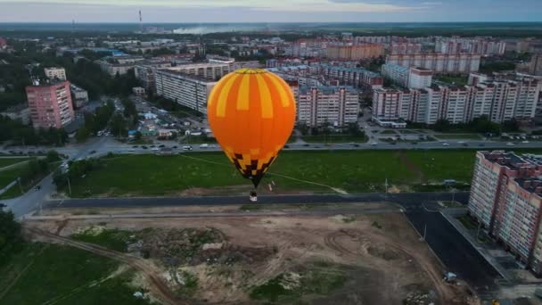 Orange air balloon slowly flies over a wasteland in the city on a summer evening — Stock video