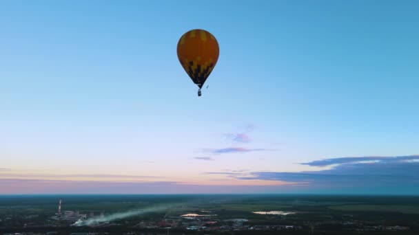 Bright air balloon flies high above city at dusk. Setting sun turned sky orange — Stockvideo