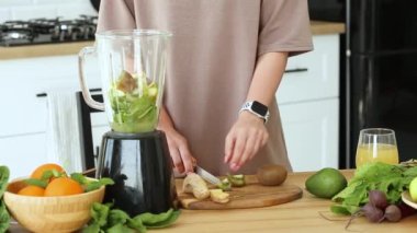 Mutfakta taze meyve suyu ile kahvaltı hazırlayan, meyveleri yakın mesafeden kesen bir kadın. Sağlıklı yaşam tarzı kavramı.