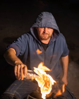 Kapüşonlu adam yanan bir şişe tutuyor. Molotof kokteyli.