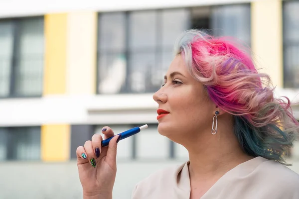 Белая женщина с цветными волосами курит электронную сигарету. — стоковое фото