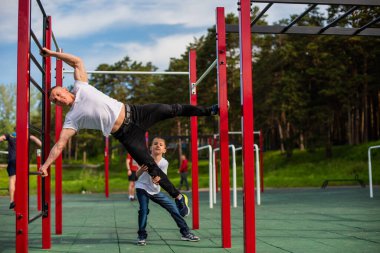 Kafkasyalı bir adam çocuk parkında bayrak dikmeyi öğretiyor..