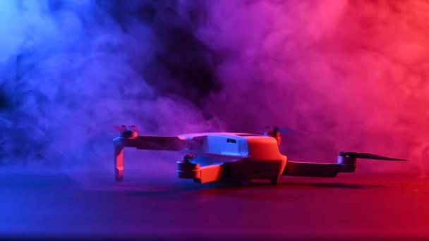 Quadrocopter dans des nuages de fumée rose-bleu sur fond noir. — Video