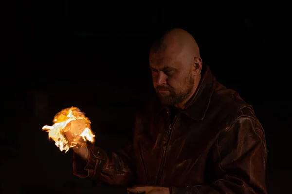 Deri ceketli kel bir adam elinde yanan bir top tutuyor.. — Stok fotoğraf