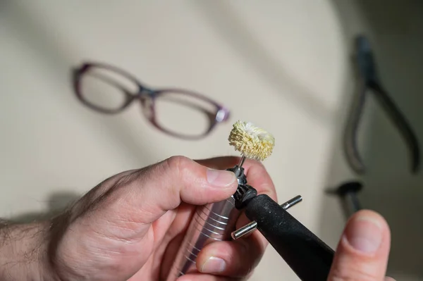 En optiker polerar glasögonbågen. En professionell optiker fixar glasögon. — Stockfoto