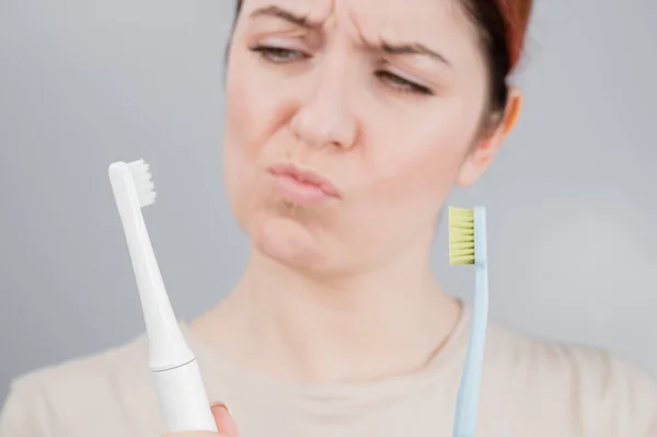 Щаслива жінка порівнює зубну щітку з електричною. Дівчина вибирає засоби гігієни ротової порожнини — стокове фото
