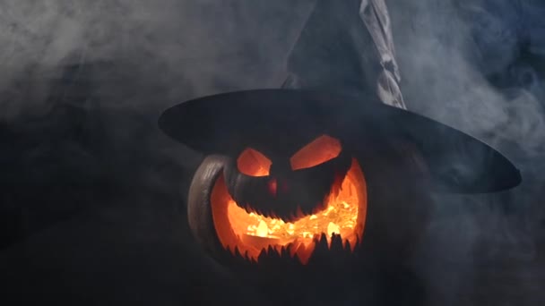 Sebuah labu menyeramkan dengan grimace diukir dalam asap. Jack o lantern dalam gelap. — Stok Video